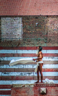 Full length of woman standing against brick wall
