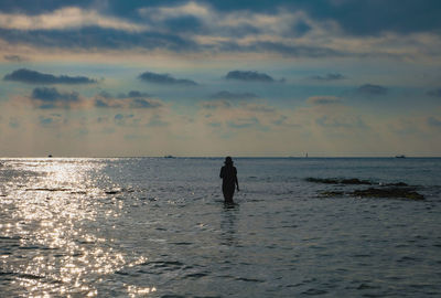 Silhouette man on beach against sky during sunset