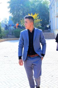 Young man looking away while standing against plants