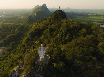 An aerial view of christ the redeemer and buddha on the mountain stands prominently