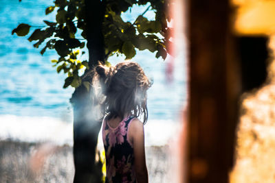 Girl standing by tree