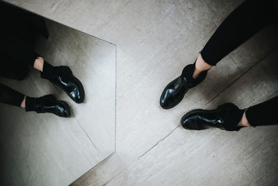 Low section of person standing by mirror with reflection on floor