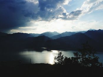 Scenic view of lake by silhouette mountains against sky