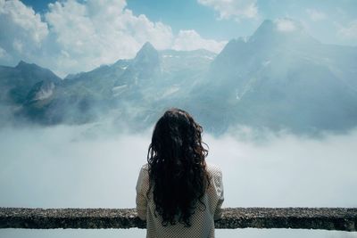 Rear view of woman standing on mountain against sky