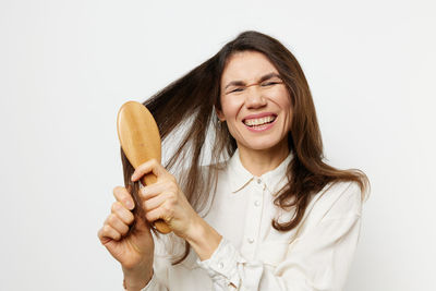 Woman combing hair against white background