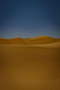 Scenic view of desert against clear blue sky