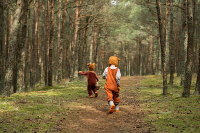 Toddler baby twins in bear bonnets playing and having fun in the woods