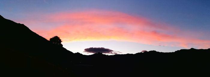 Silhouette mountains against dramatic sky during sunset