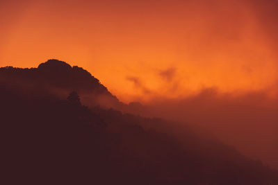 Scenic view of silhouette mountains against orange sky