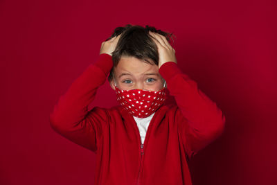 Close-up portrait of boy against red background