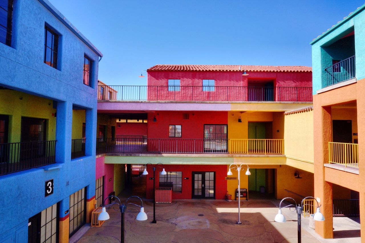 architecture, building exterior, built structure, clear sky, residential building, residential structure, window, house, blue, balcony, building, city, sunlight, outdoors, day, sky, facade, no people, residential district, railing