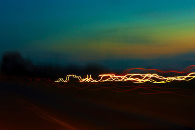 Light trails on road against sky at night