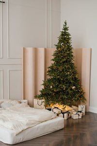 Christmas tree with gifts in the interior of a stylish bedroom