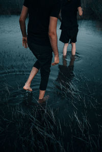 Low section of couple walking in lake