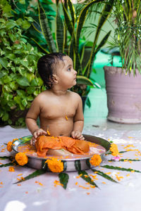 Cute toddler baby boy bathing in decorated bathtub at outdoor from unique perspective