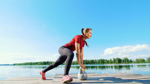 Beautiful, athletic young blond woman doing different exercises with weights, dumbbells, squats. 