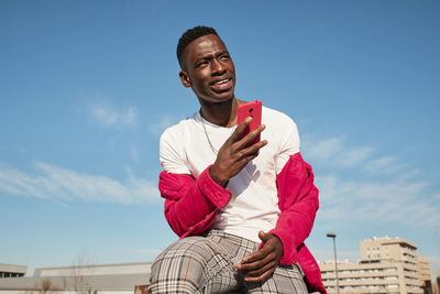 Young man in red jacket looking at smart phone outdoors