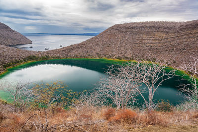 Scenic view of lagoon at isabela island by sea against cloudy sky