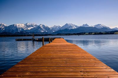 Wooden pier over lake against snowcapped mountains