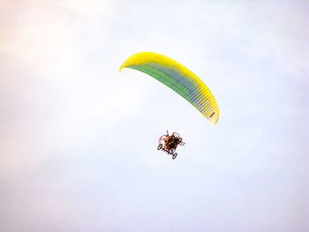 Low angle view of person powered paragliding against sky