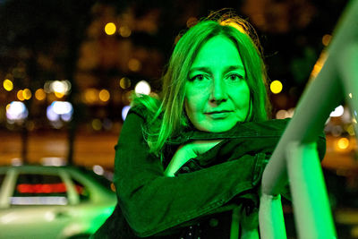 Portrait of a young woman in a night city in neon green on a summer evening. city lights.