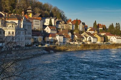 Houses by river in town against sky