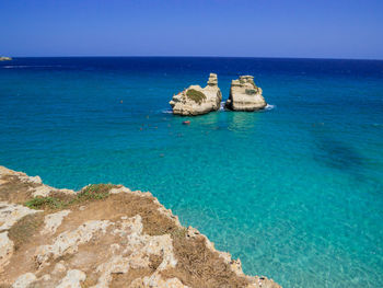 Scenic view of rocks in sea against clear sky