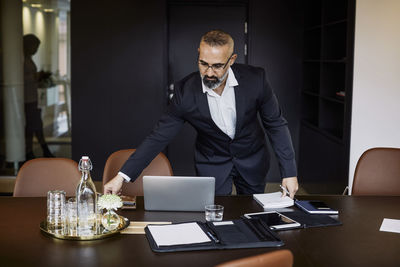 Confident male professional working at conference table in board room