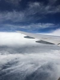 Aerial view of airplane wing against cloudy sky