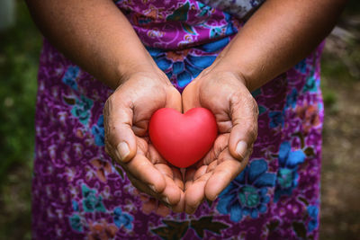 Midsection of woman holding heart shape