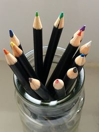 Close-up of colored pencils in glass jar on table