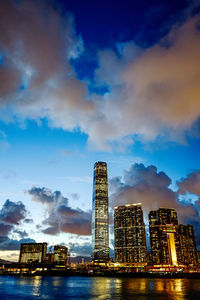 Illuminated buildings in city against cloudy sky