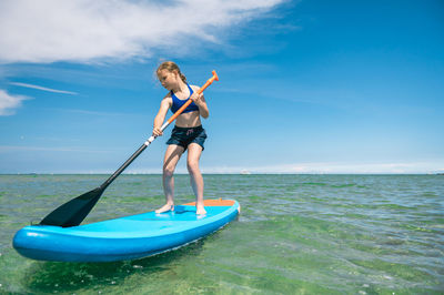 Full length of woman standing in sea against sky