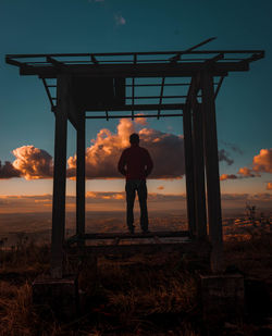 Rear view of man standing against sky during sunset