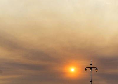 Low angle view of weather vane at sunset