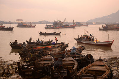 Fishing boats moored at harbor during sunset