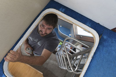High angle portrait of man with drink can sanding in yacht