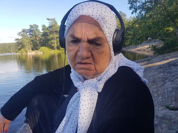 Portrait of young woman standing against lake