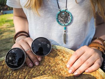 Midsection of woman holding hat and sunglasses