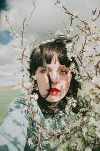 Portrait of woman with red flowers against blurred background