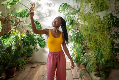 Young woman standing against plants