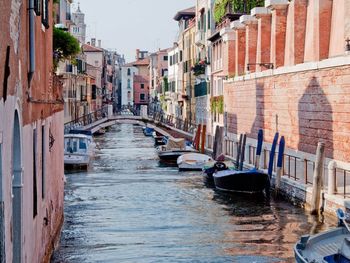 Boats in canal amidst buildings in city