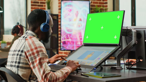 Rear view of man using laptop at office