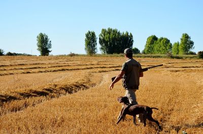 Hunter walking with dog on landscape