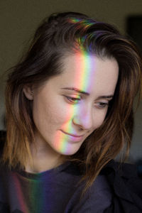 Rainbow lights falling on woman face at home