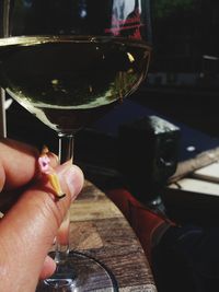 Close-up of hand holding wine glass on table