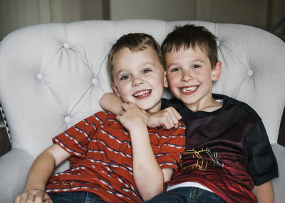 Portrait of cheerful brothers sitting on chair