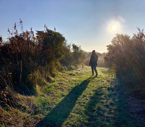 Man walking on field against bright sun