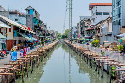 Canal amidst buildings in city against sky