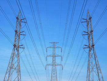 Low angle view of electricity pylon against clear blue sky